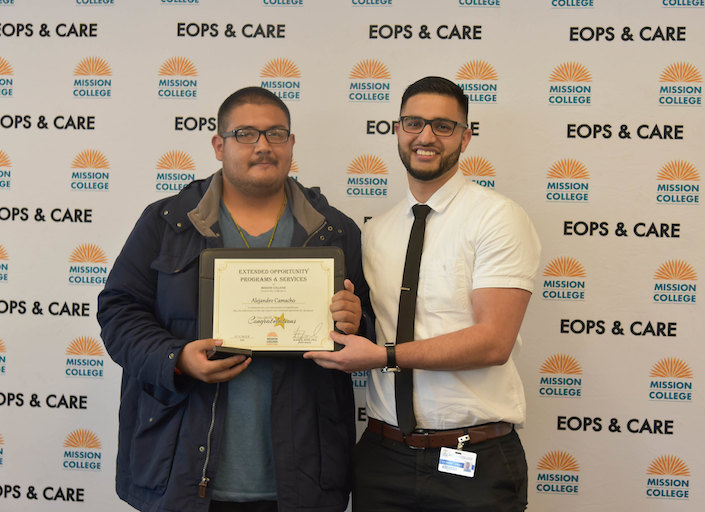Alejandro Zavalo with a male student. They each hold part of a certificate against a backdrop that reads "EOPS/CARE".