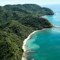 An aerial shot of Costa Rica with a bright blue ocean and curving beach,