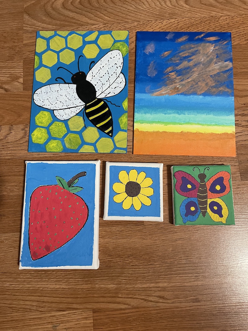 Four small colorful works of art on a table top.