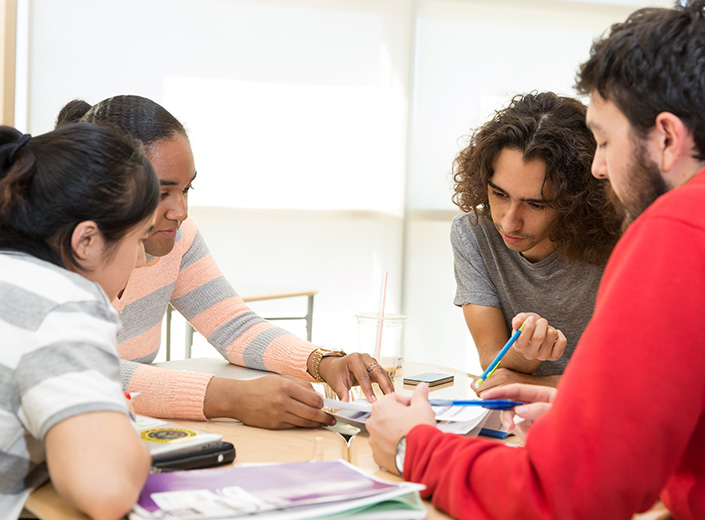 Four students work together at a table in a classroom.