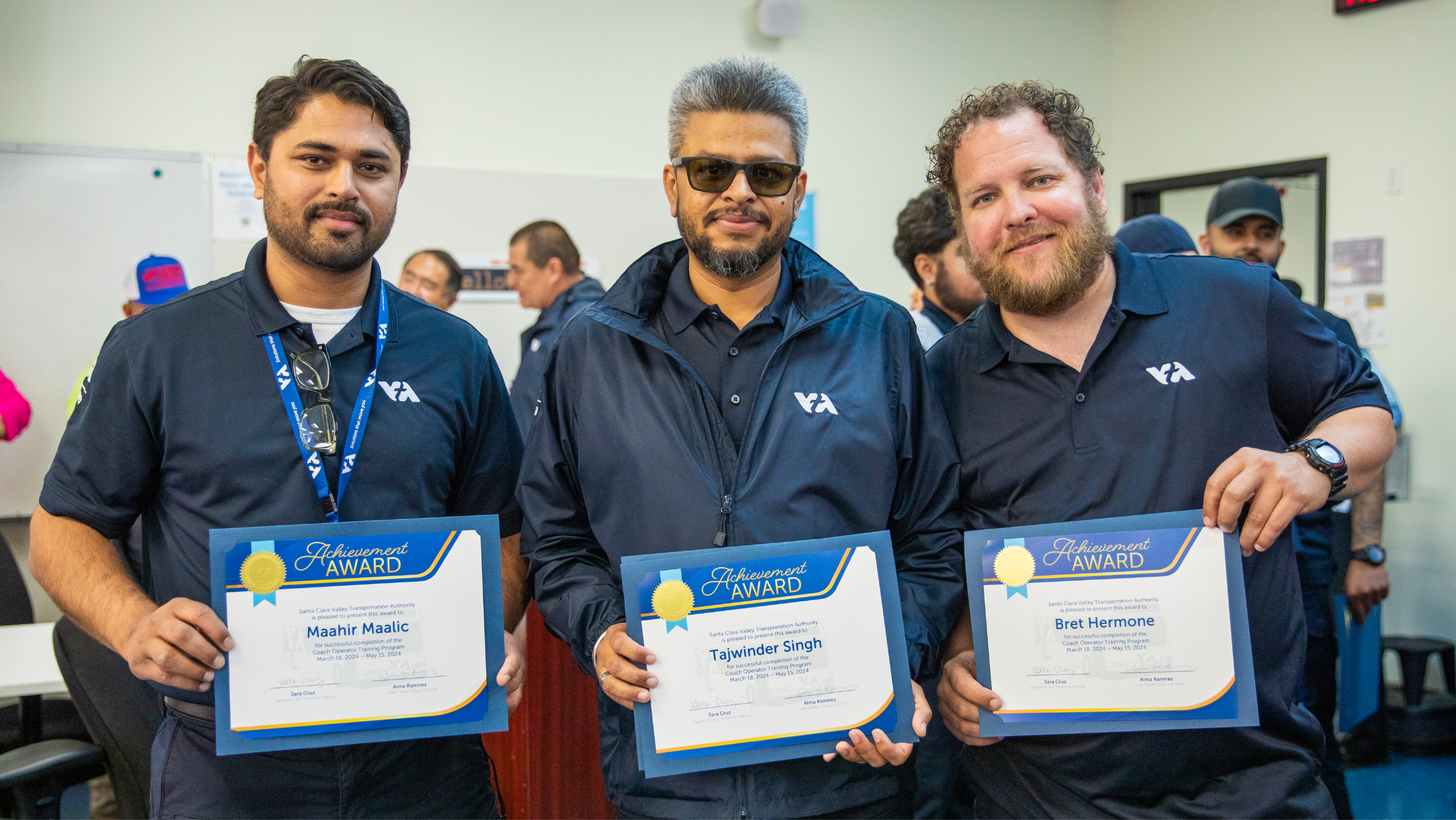 Three men in VTA uniform polos smiling while proudly holding their Achievement Award certificates.