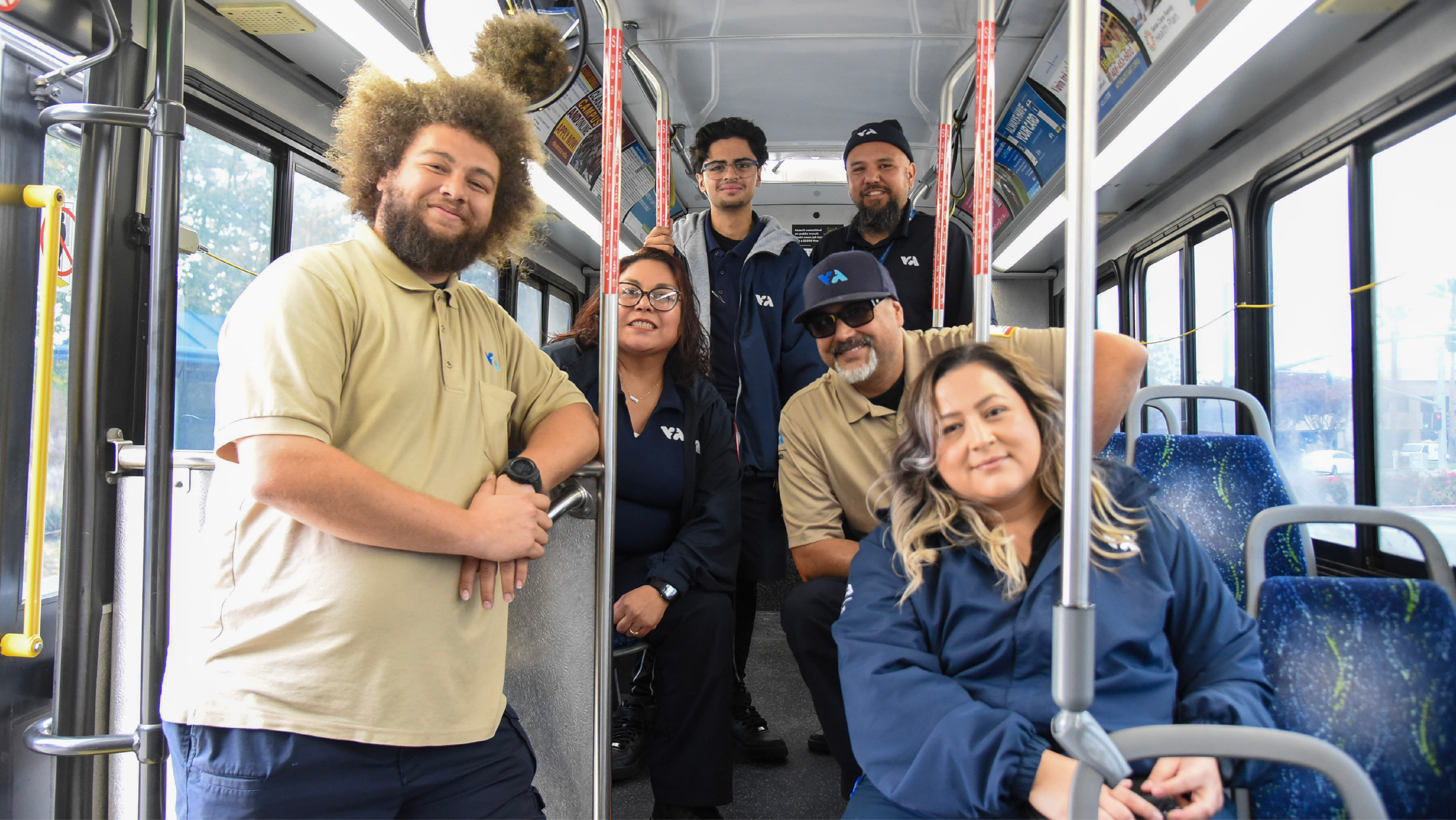 Six VTA apprentices in uniform posing together inside a transit bus.