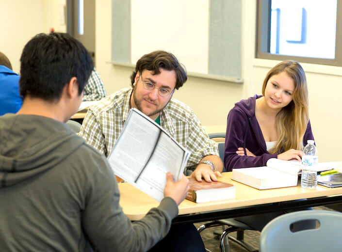 Students discuss their work in a college classroom.