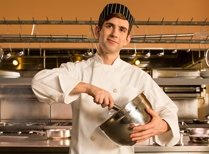 Hospitality Management student mixes something in a metal bowl.