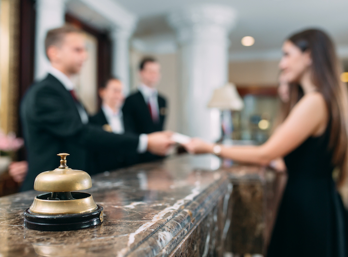 Hospitality Management - a hotel desk reception clerk hands a key across the desk.