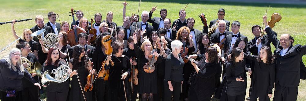 Members of the Mission Symphony pose in black with their instruments on the lawn.