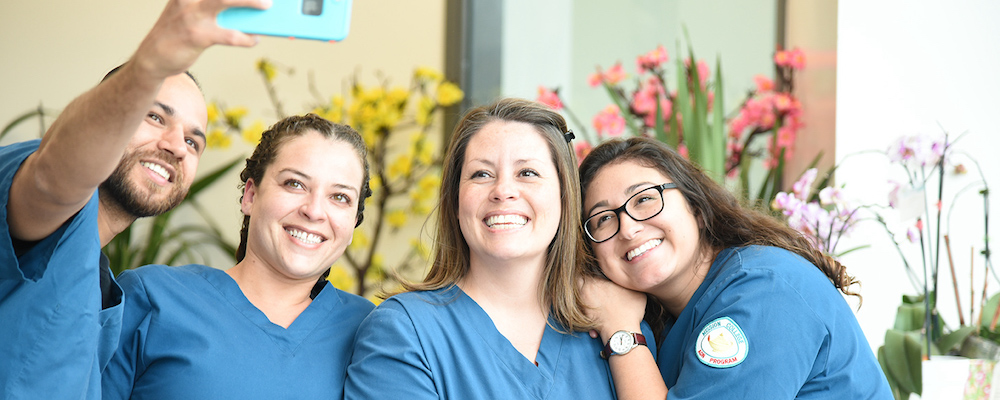 Four nursing students in scrubs take a selfie