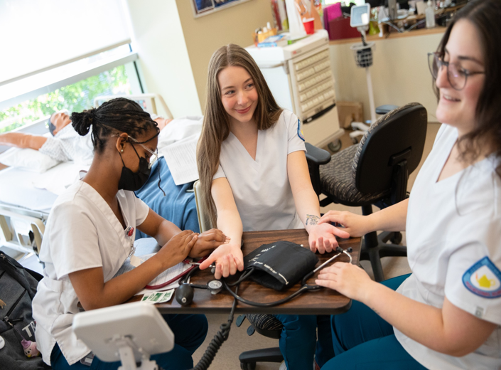 Teen girls practice Nursing skills in a lab at Mission College.