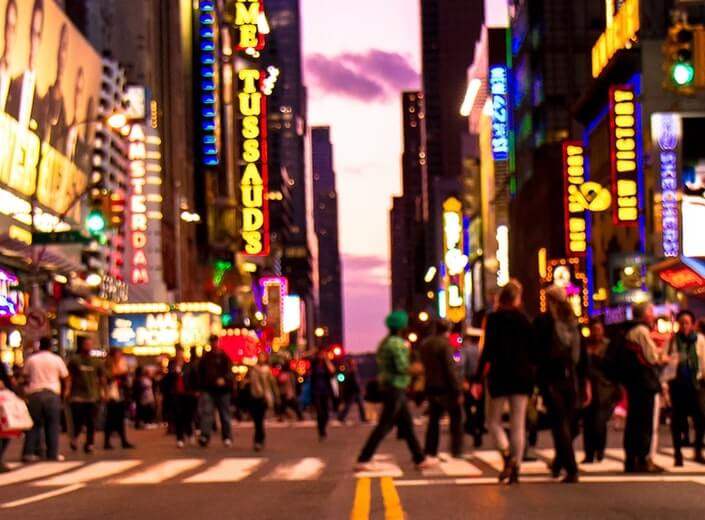 Busy night in Times Square. Lots of people are crossing the street.