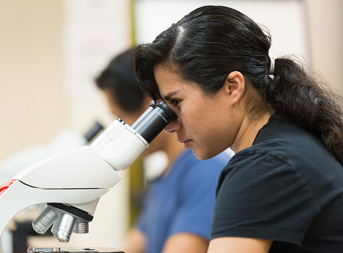 female student at a microscope