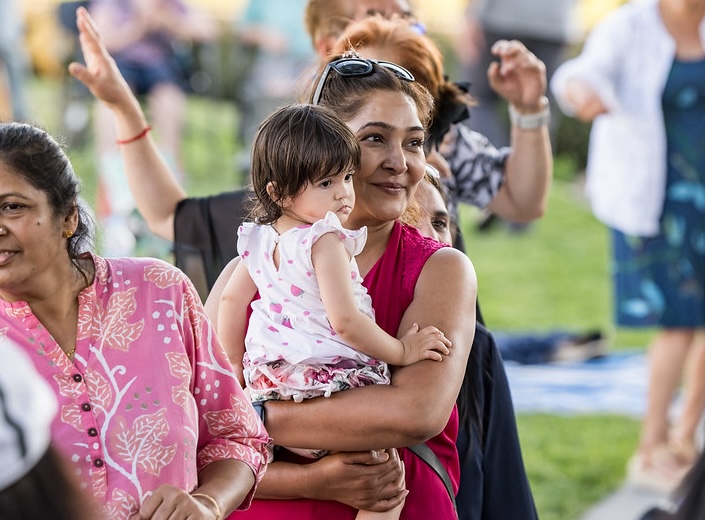 Baby held by concert atendee, a woman with dark hair and brown skin.