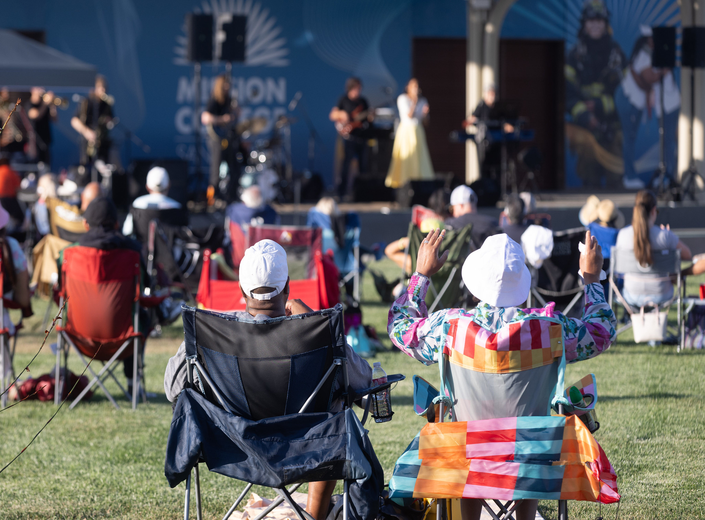 Five friends cheering and posing together on the lawn during the concert series