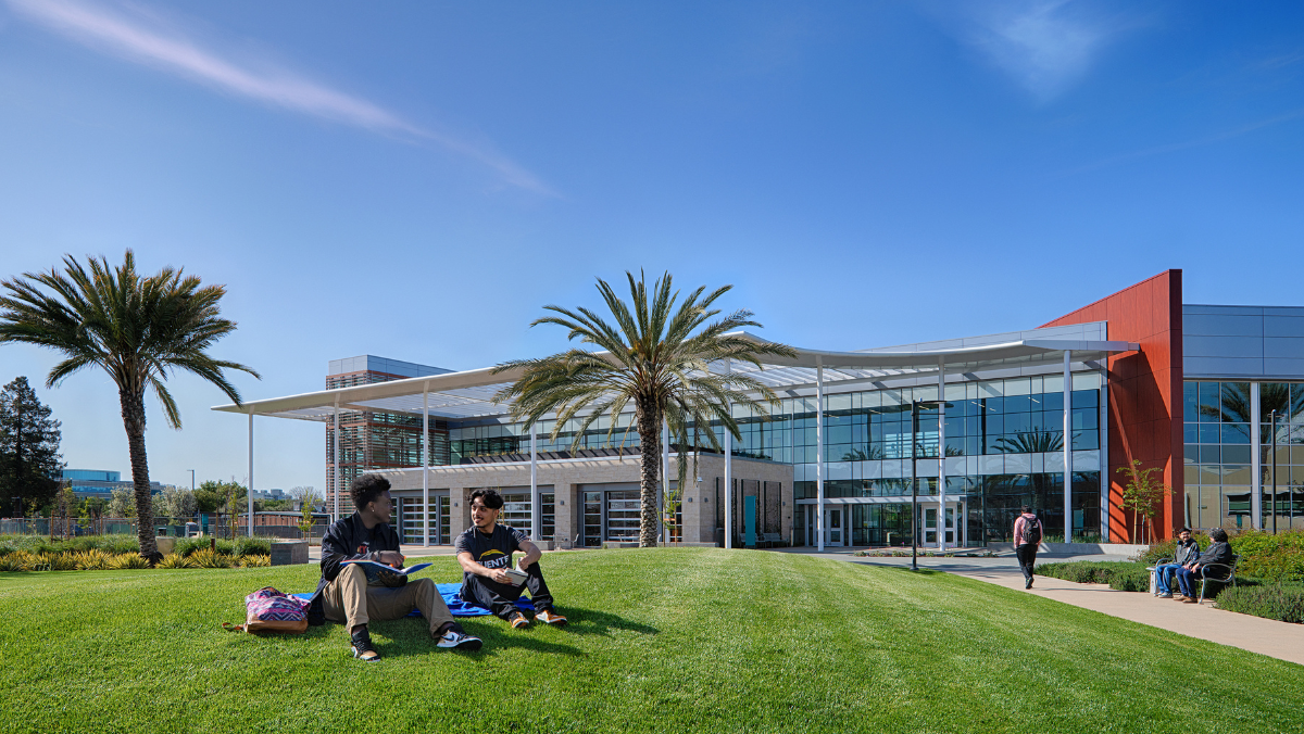 Two students talking on small mound on campus