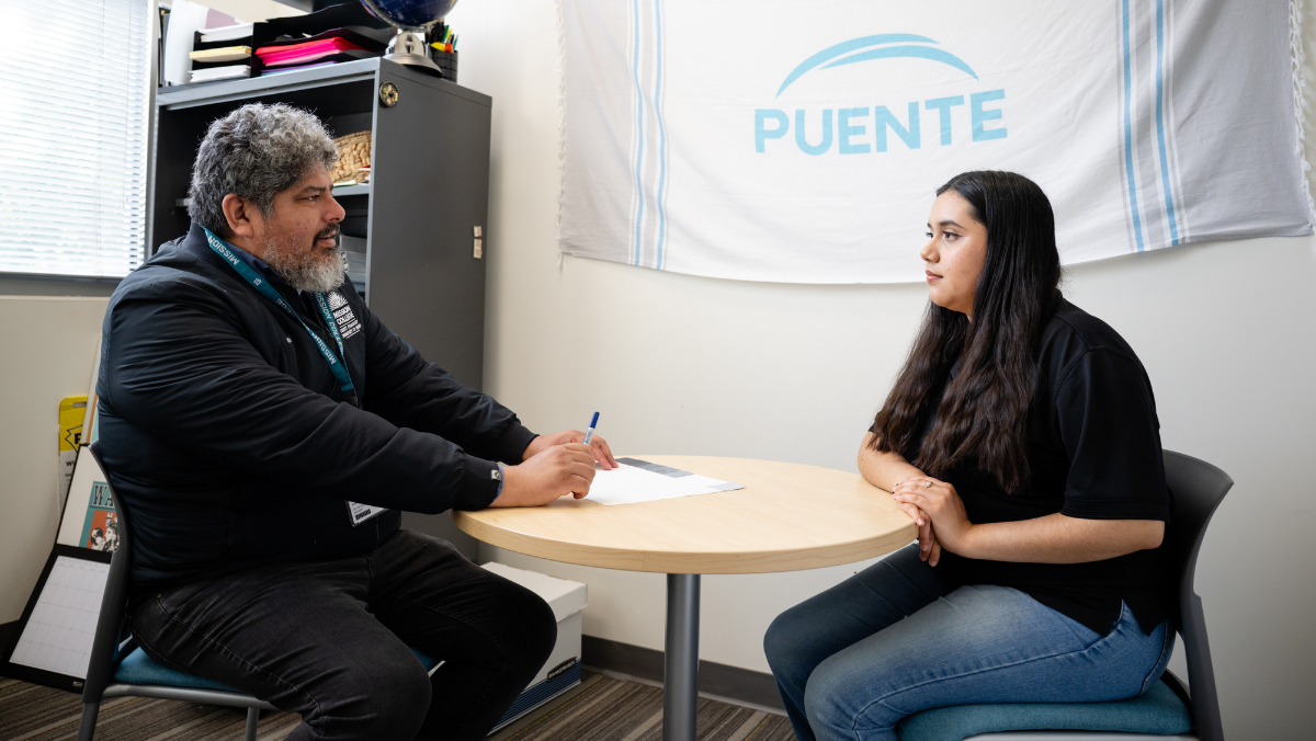 Employee working with students under Puente flag