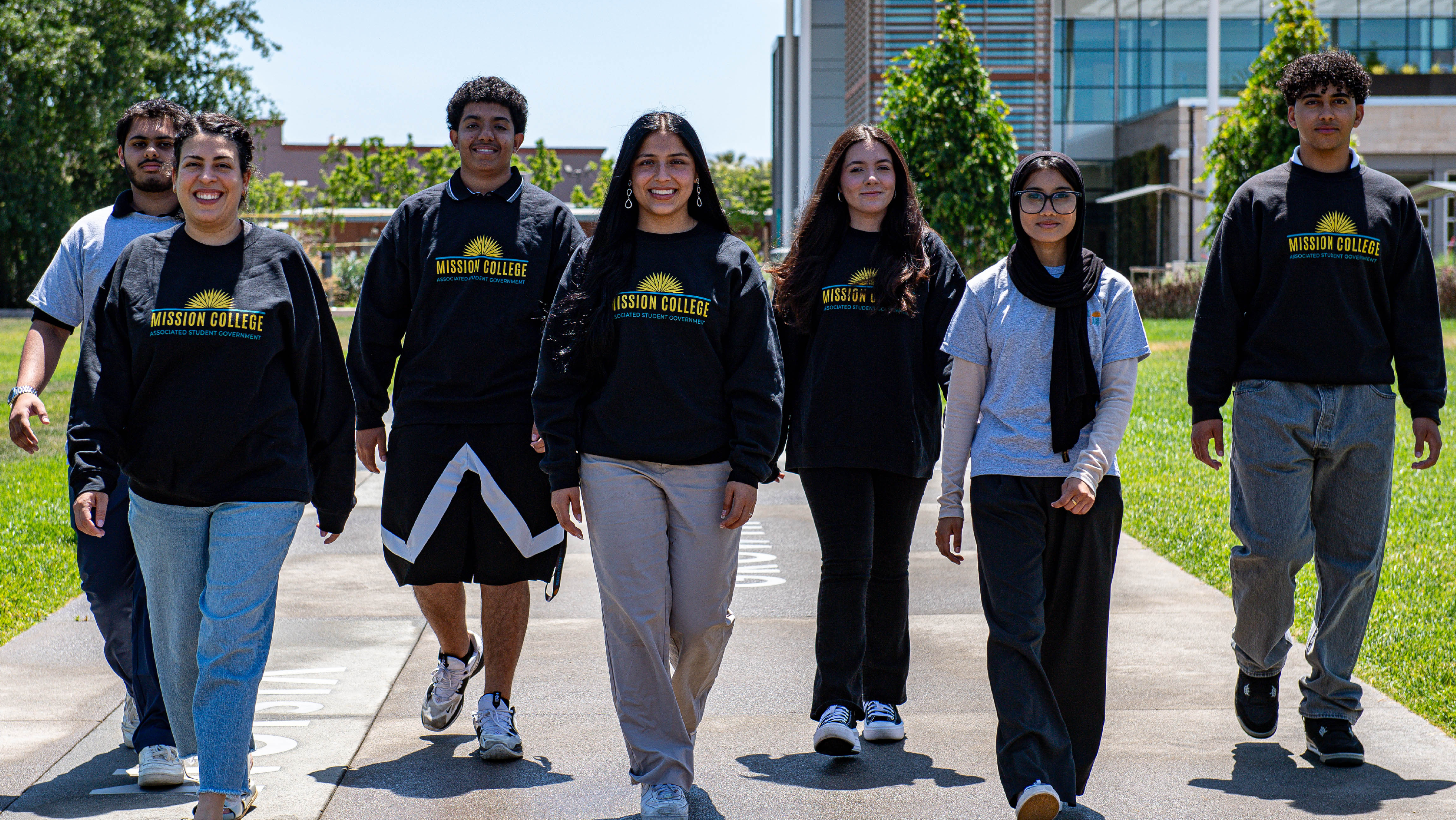 A group of six Associated Student Government leaders walking together along a campus pathway.
