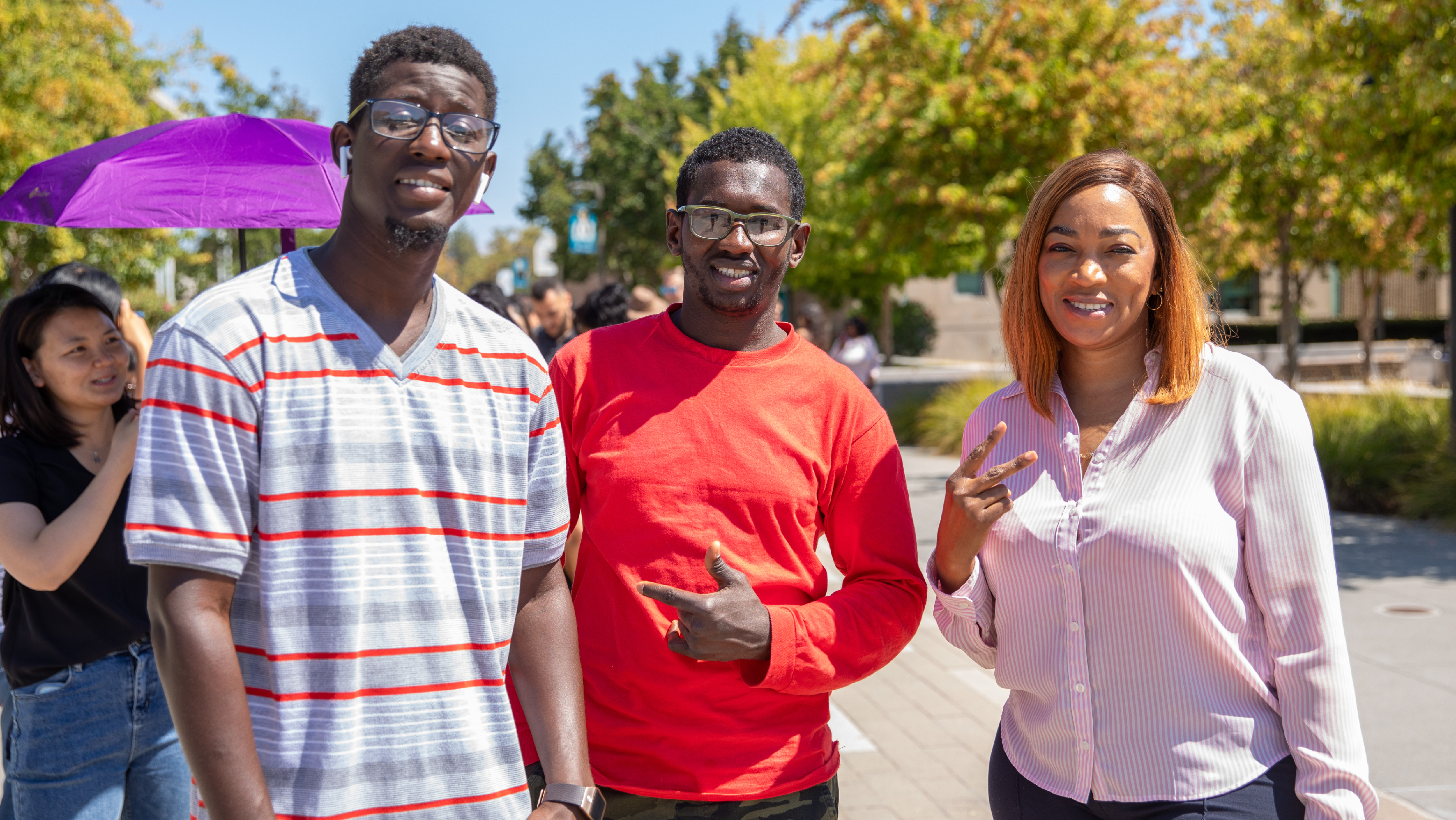 Three students standing outdoors while one holds a paper admissions flyer and information guide.