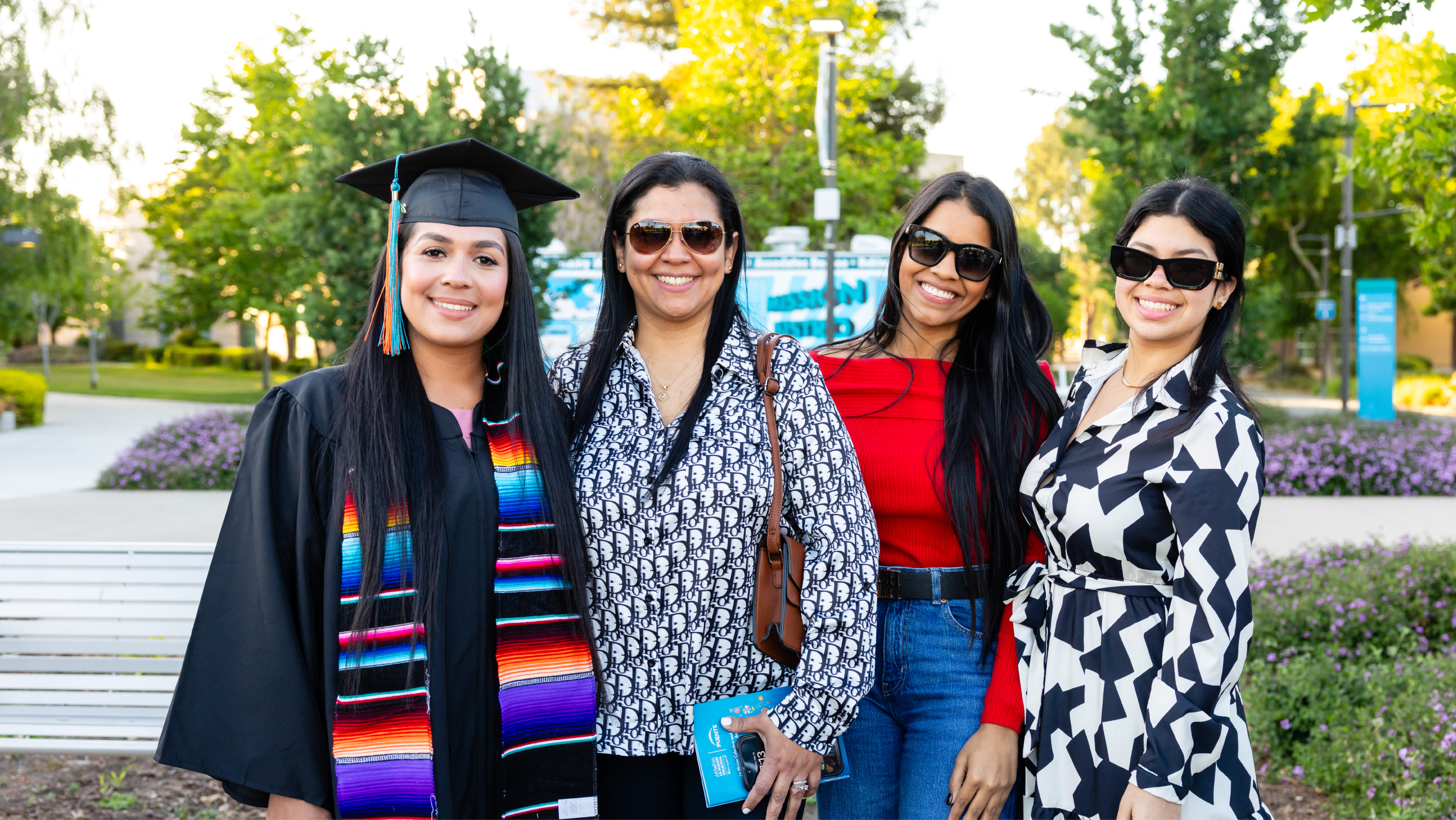 Excited Mission College graduate celebrating and holding up a diploma cover during commencement.