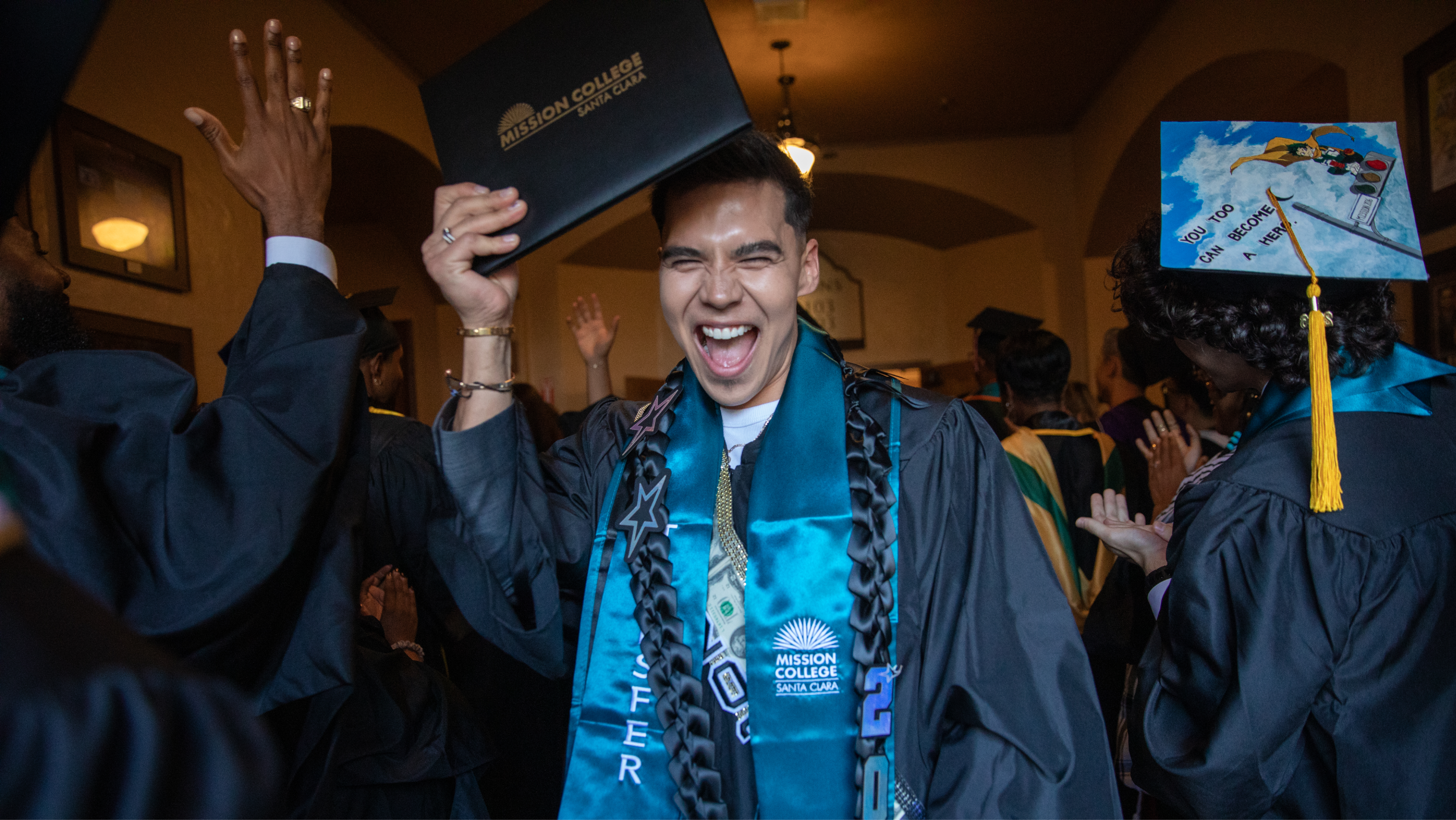 Smiling Mission College graduate in a cap, gown, and stole at graduation.