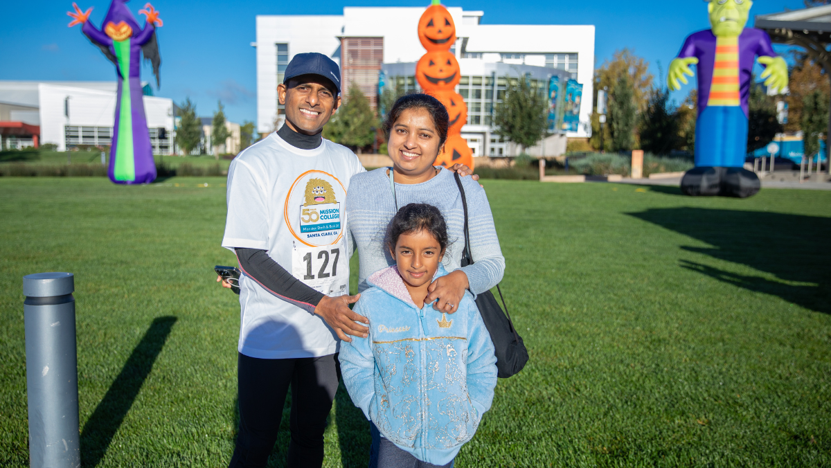 A family poses in front of Halloween inflatables on the Mission College lawn before the Monster Dash & Bash 5K.