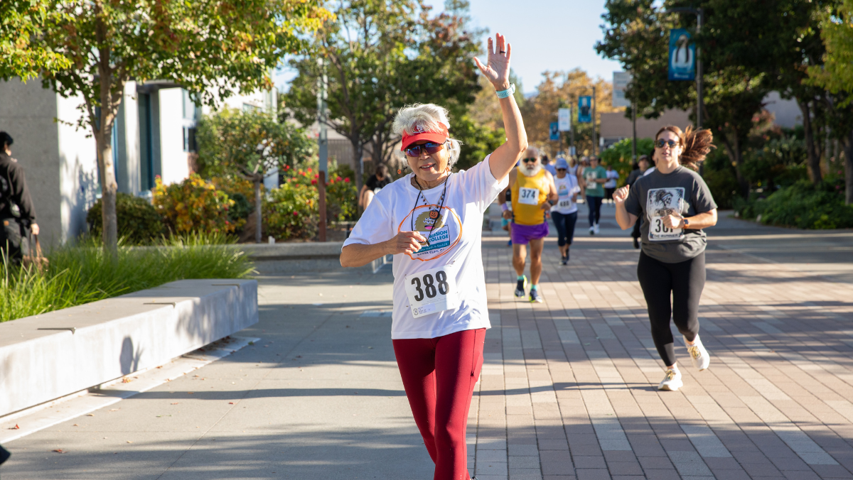 A participant waves to the camera while completing the Monster Dash & Bash 5K on the Mission College campus.
