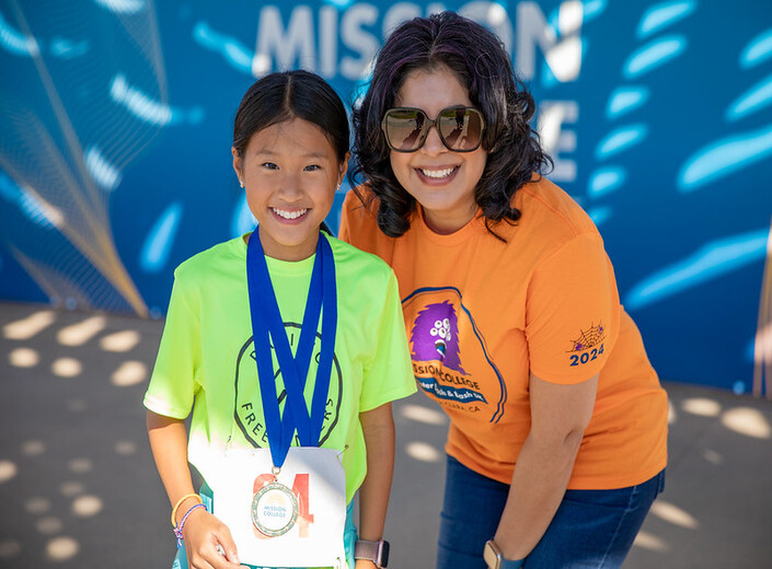 President Awan poses with young girl as she receives a medal.