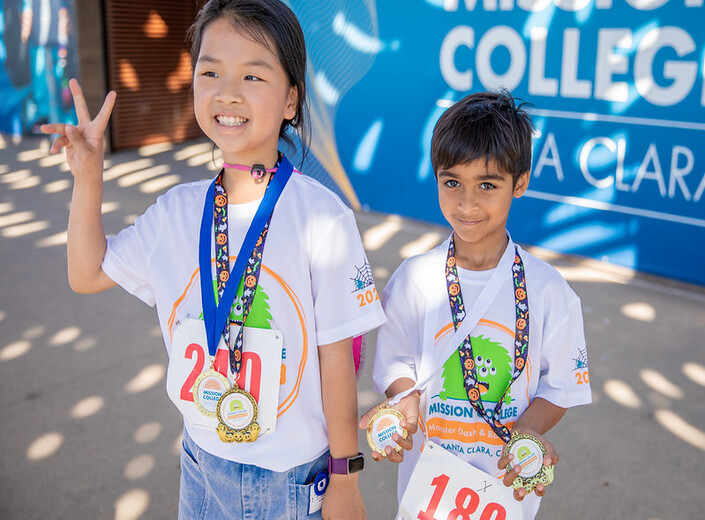 A young girl and boy pose with medals.