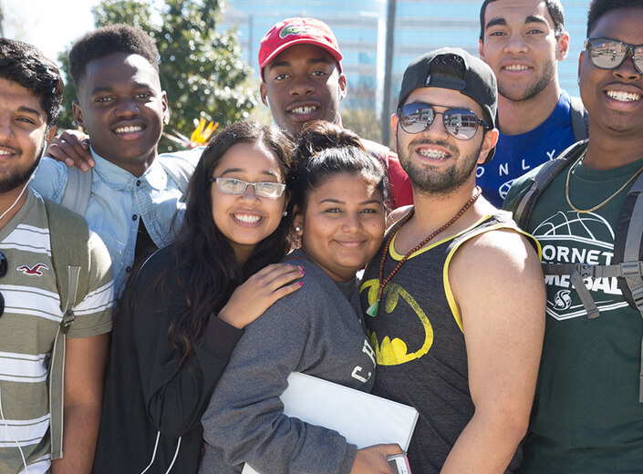 Group of students posing in a group outside on a college campus.