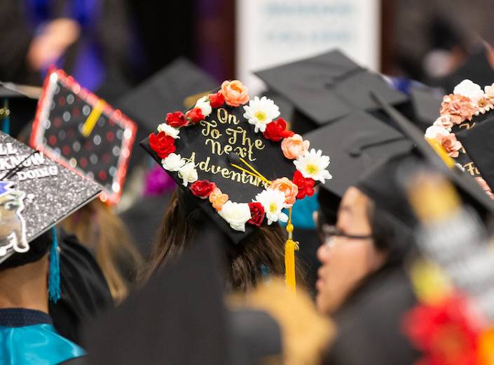 Students in graduation/commencement caps (decorated) from above.