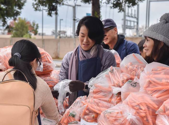 A woman with short black hair assists at the 2nd Harvest food bank for Mission College.