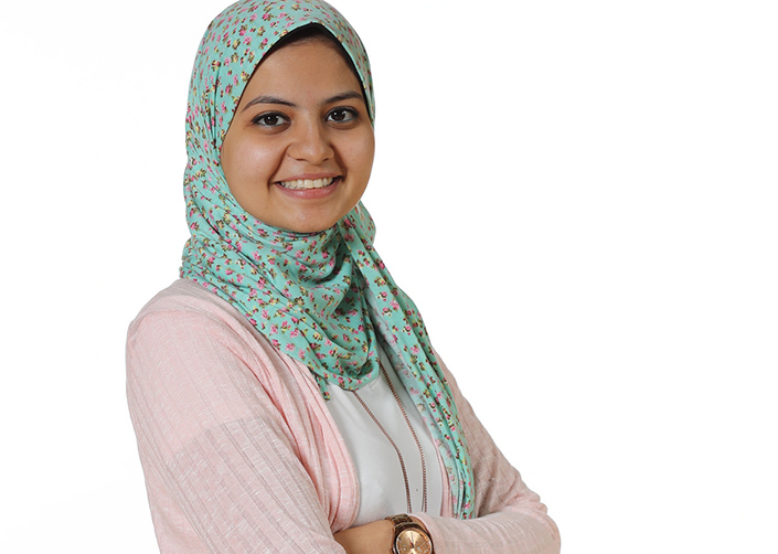 Young woman in floral hijab crossed her arms in front of her chest and smiles.