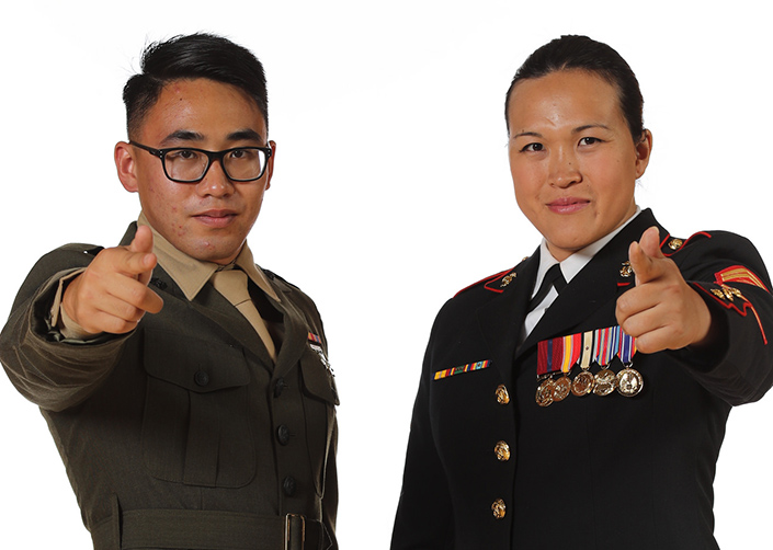Male and female veterans in uniform point toward the camera against a white background.