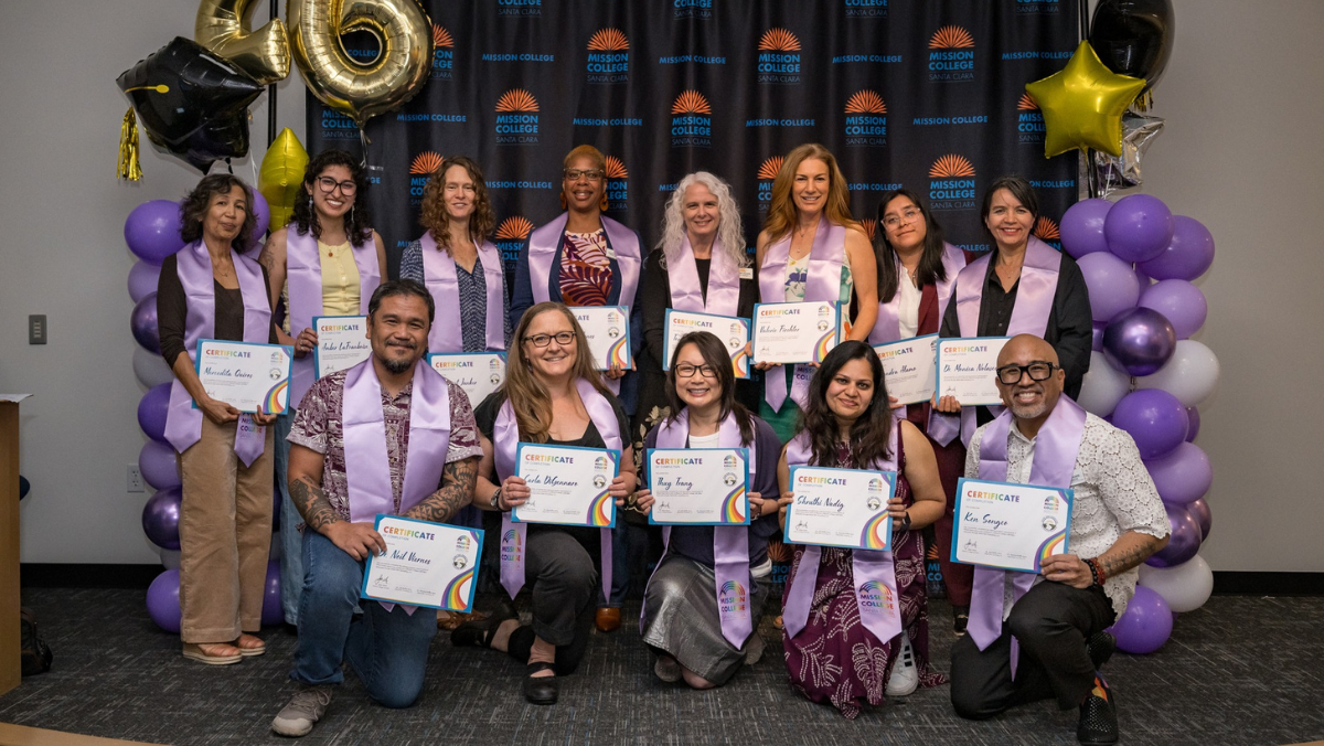 A group photo of adults posing indoors with purple stoles and framed award certificates against a Mission College backdrop, framed by purple and gold balloon towers.