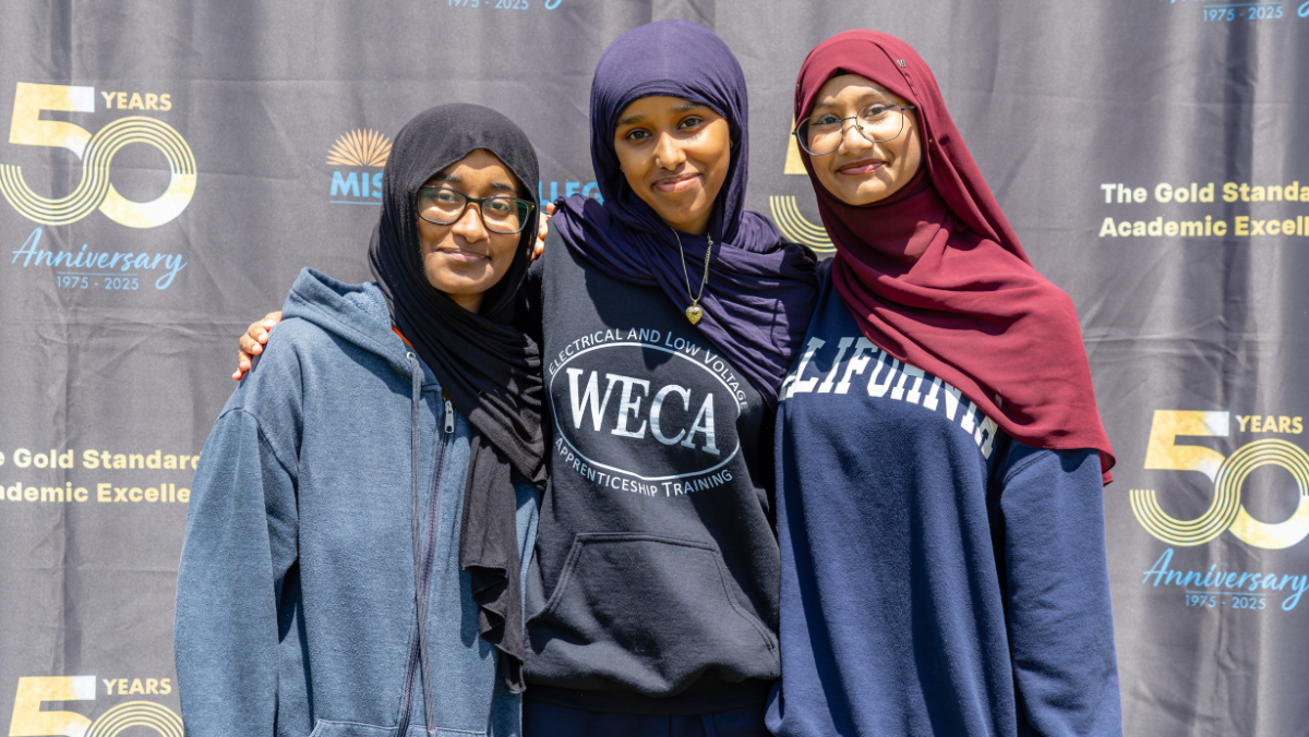 Smiling students in front of banner
