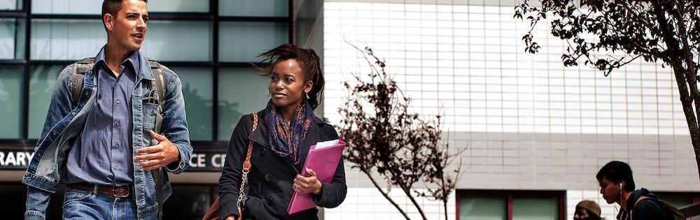 A male and female student stroll on campus.