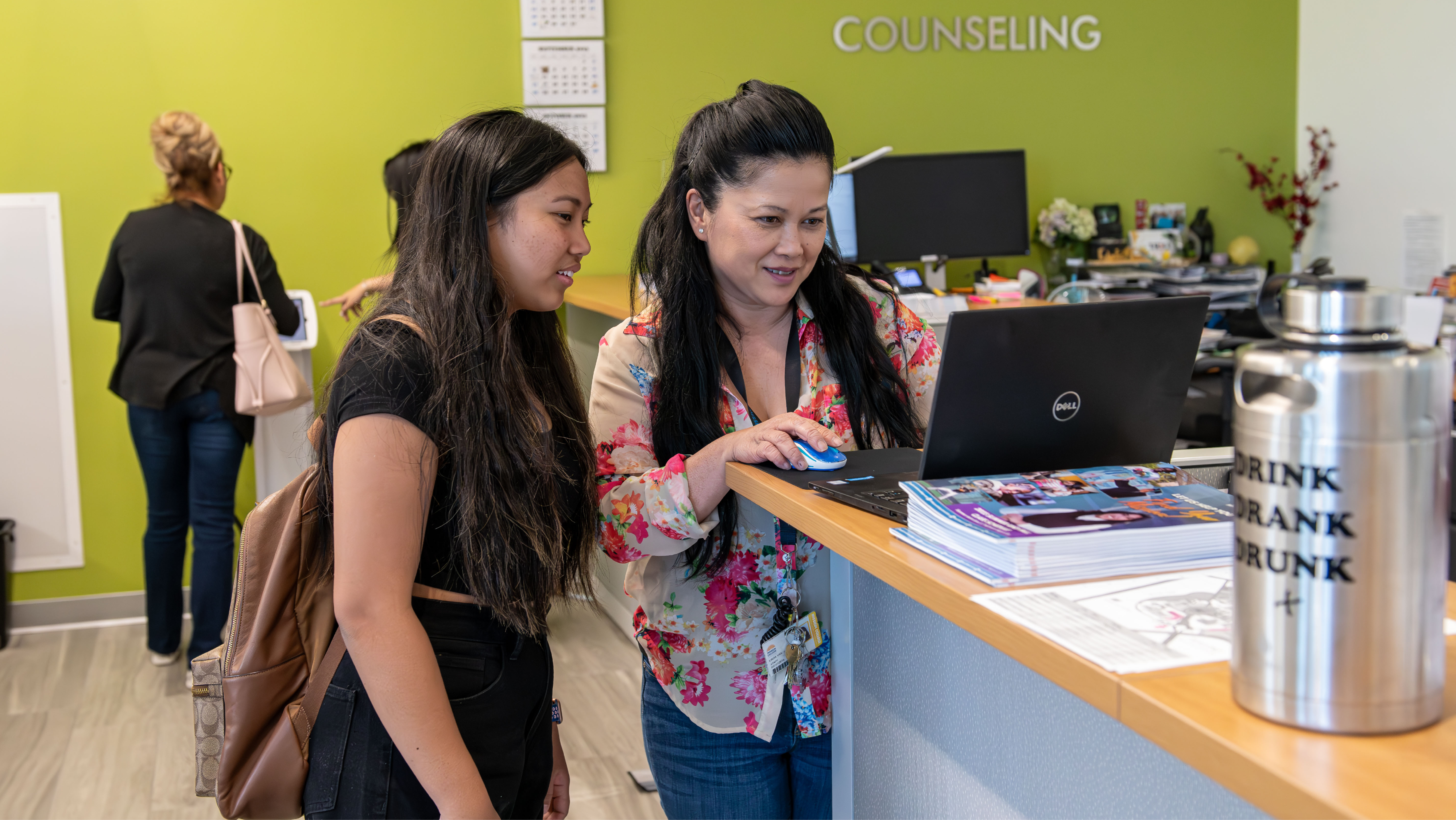 A female counselor helping a female student review information on a laptop at the Counseling counter.