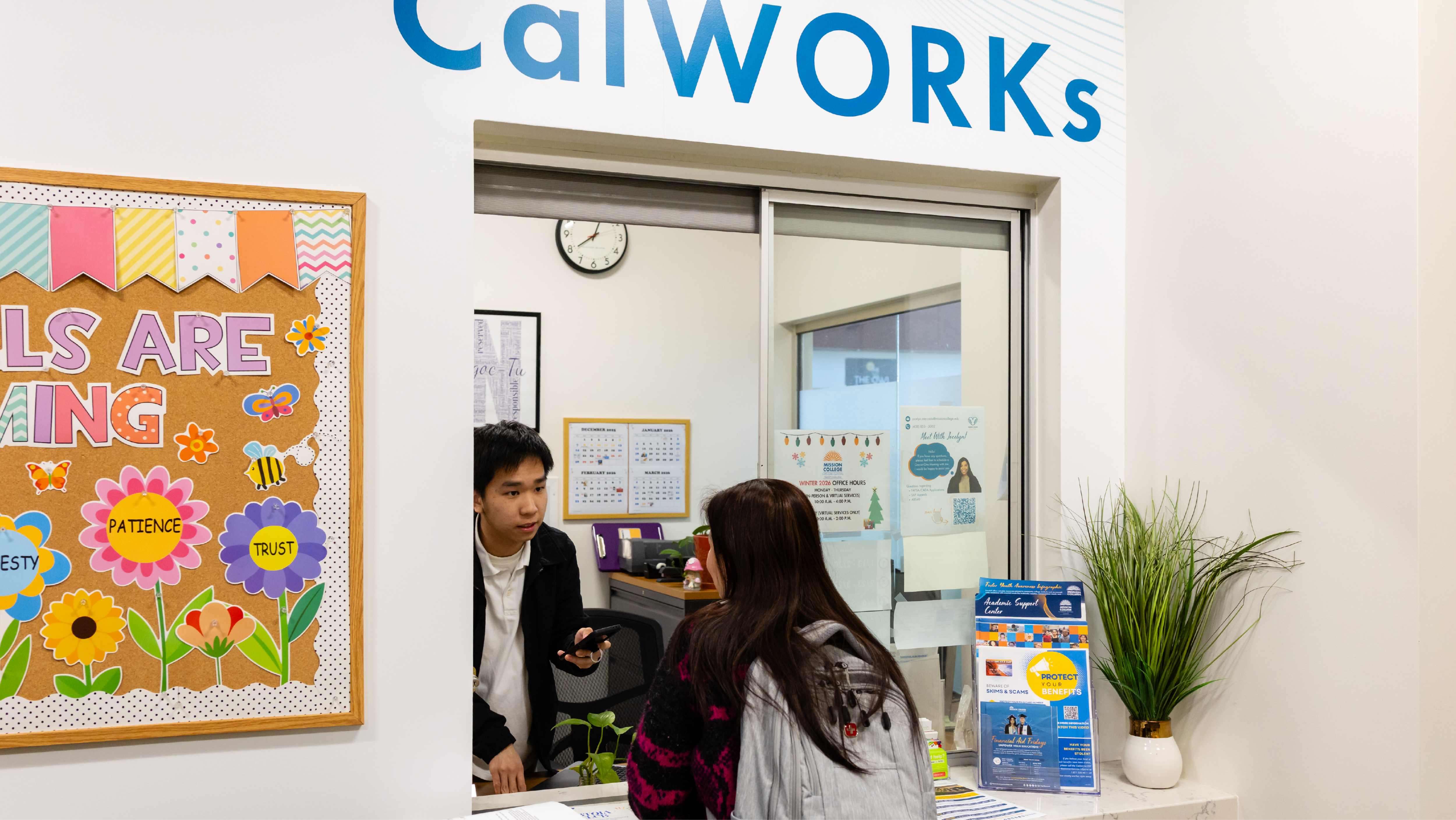 A female student pointing to a science poster presentation while speaking to a colleague.
