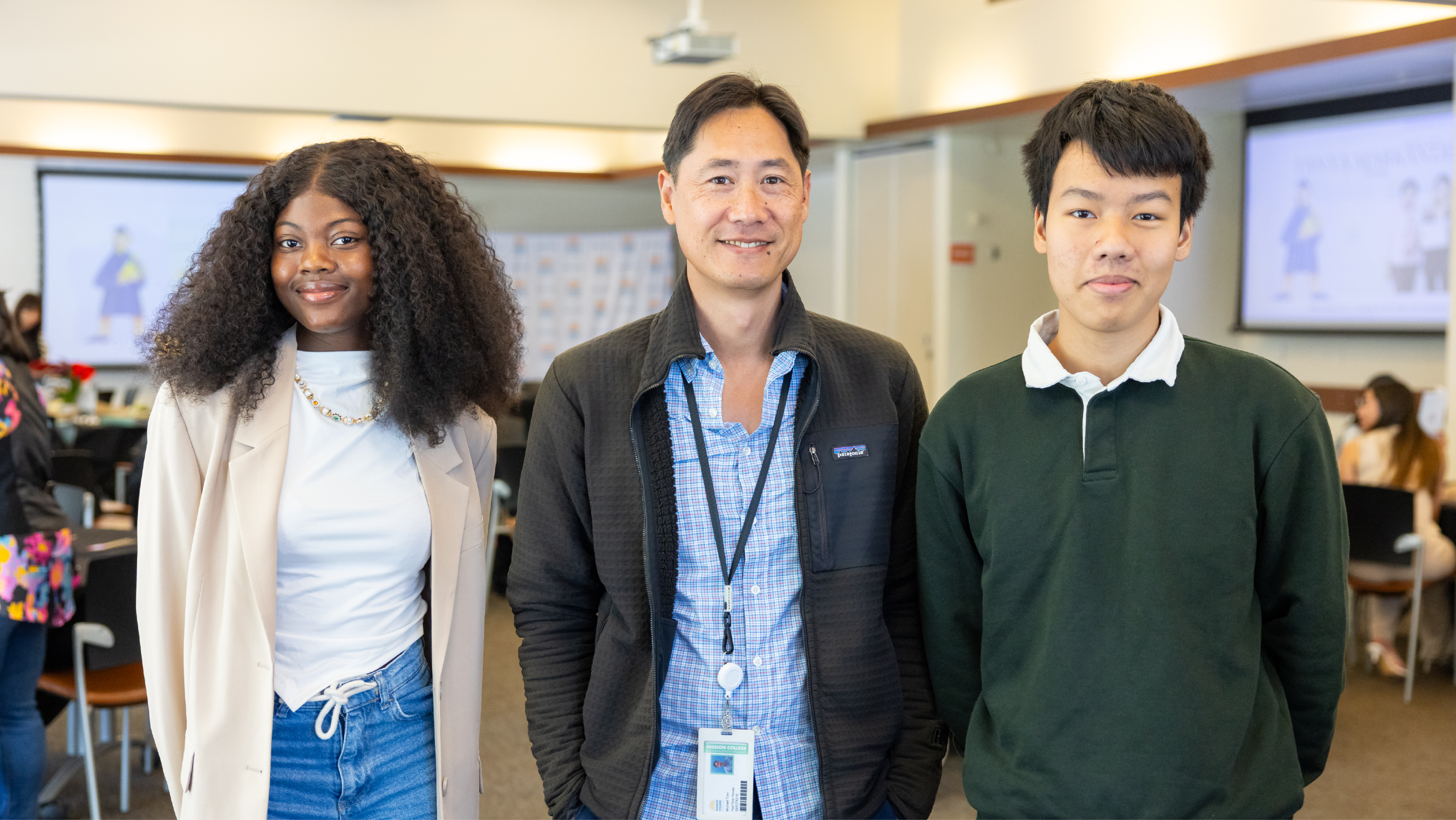 A Mission College staff member posing with two international students in a campus event hall.