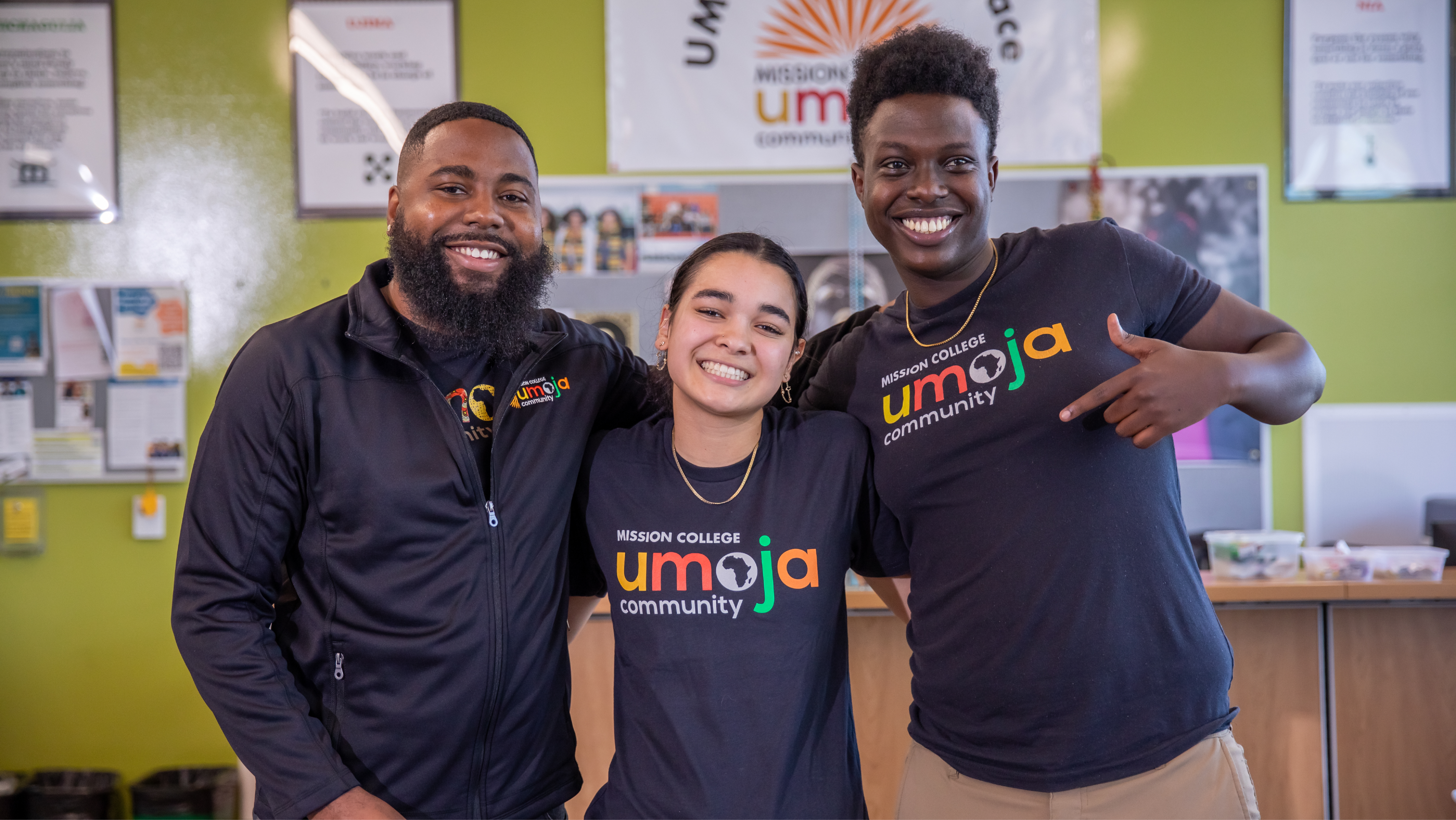 Three Mission College Umoja students smiling and posing together inside the Umoja Village Space.