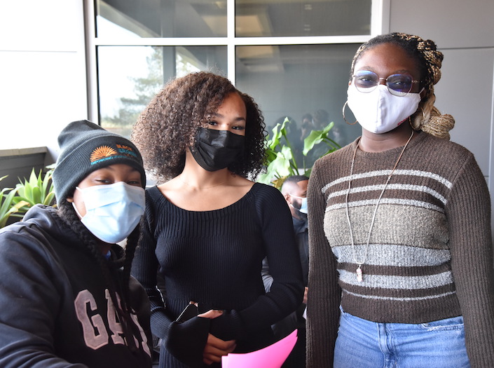 Umoja students - three young women in face masks outside.