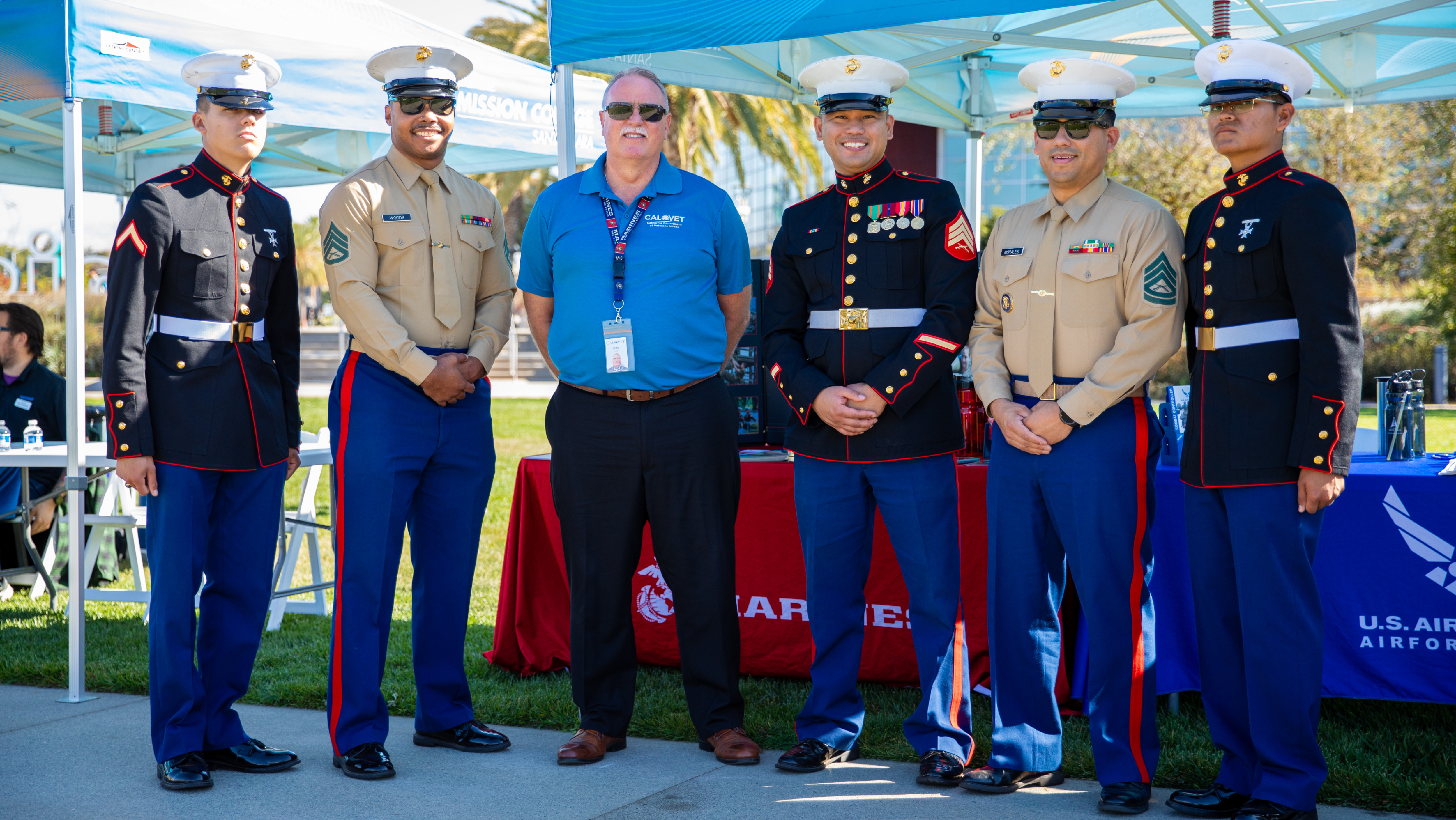 Five military service members in dress uniforms posing outdoors in a row alongside a representative in a CalVet polo shirt.