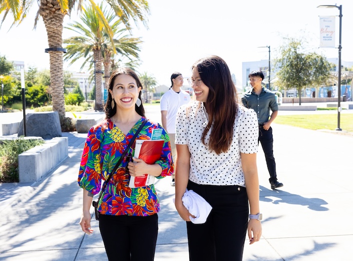 Two young women walking and smiling.