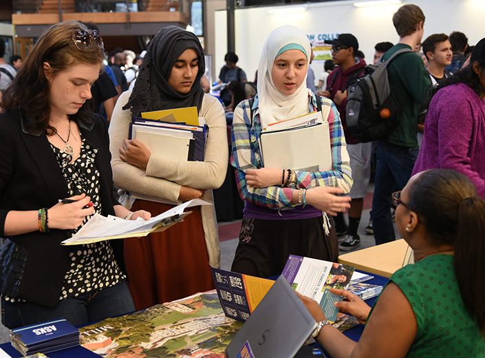 three students talking to a college rep